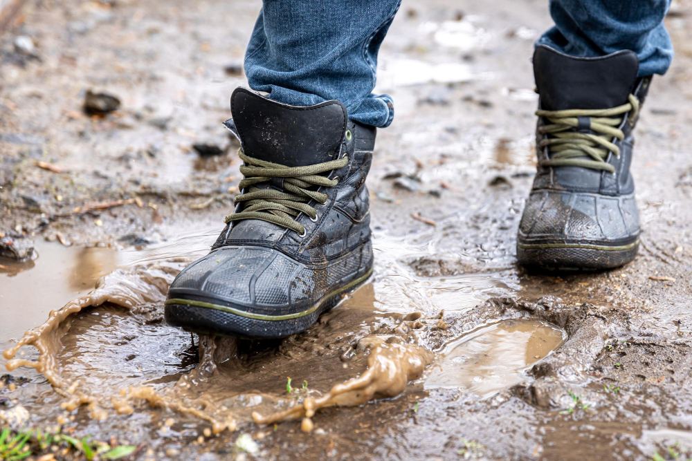Chaussures de marche dans une flaque de boue après une coulée